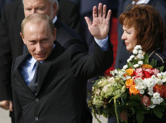 Russian President Vladimir Putin waves on arrival, accompanied by his wife Ludmila Alexandrovna Putina