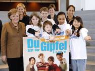 Merkel, Jones and young people in front of the competition poster